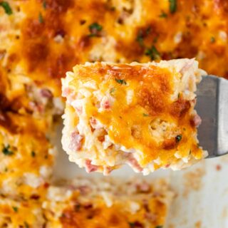 Cheesy Ham and Hash Brown Casserole in casserole dish with scoop closeup 1x1
