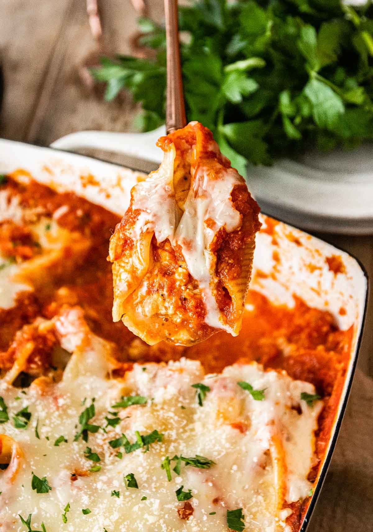 Chicken Parmesan Stuffed Shells in baking pan with closeup of spoonful
