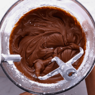 Cocoa frosting in glass bowl with mixing paddle