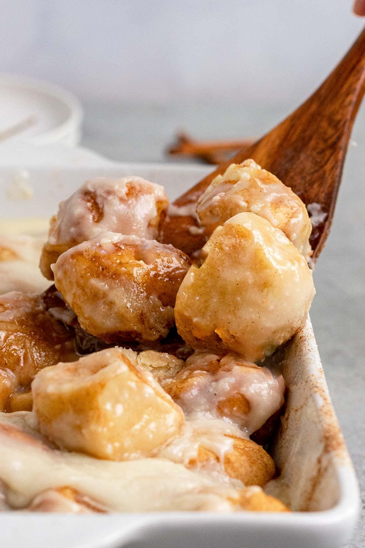 Cinnamon Roll Bites scooping out of baking dish