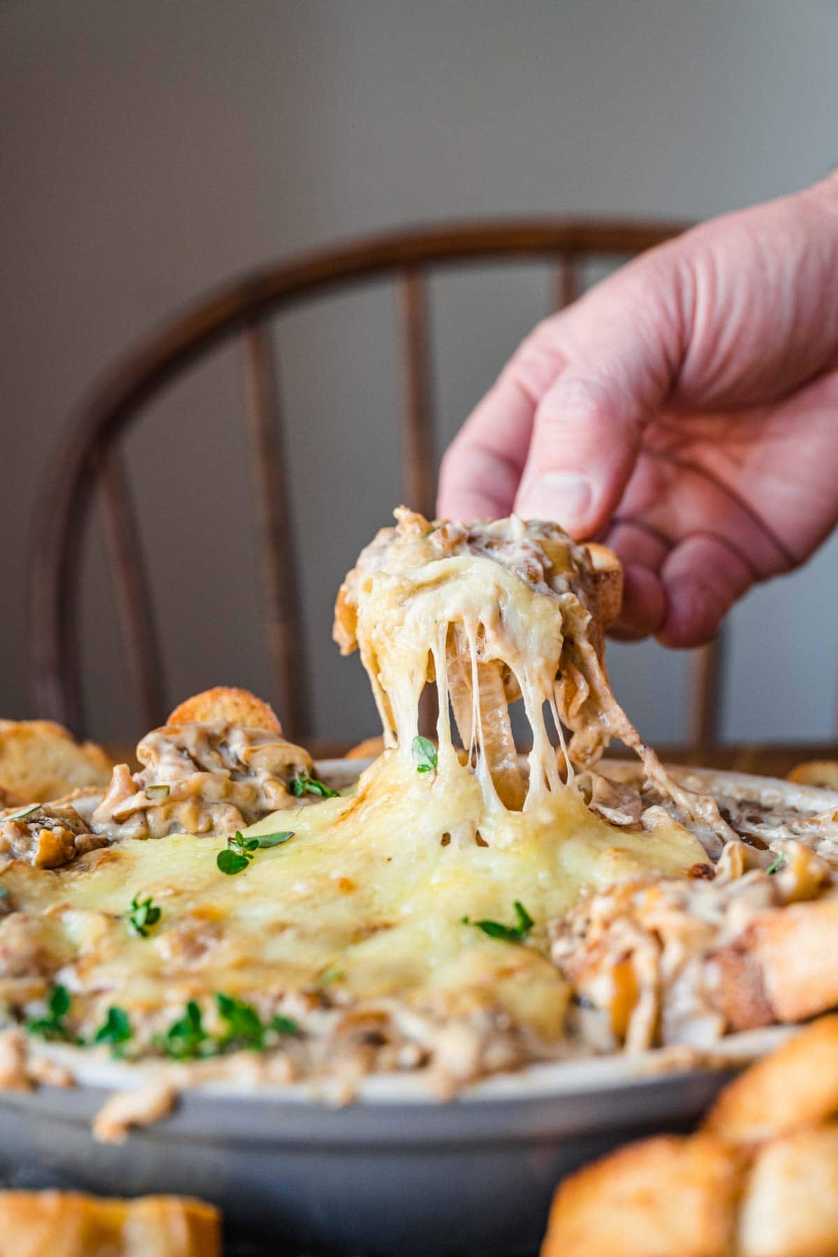 French Onion Soup Dip in serving dish dipping a chip