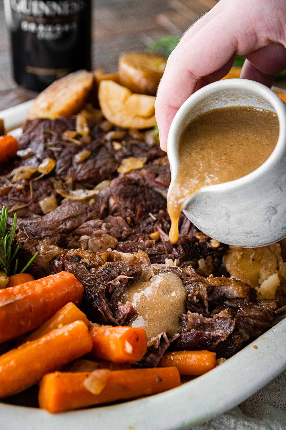 Guinness Pot Roast on serving platter pouring gravy