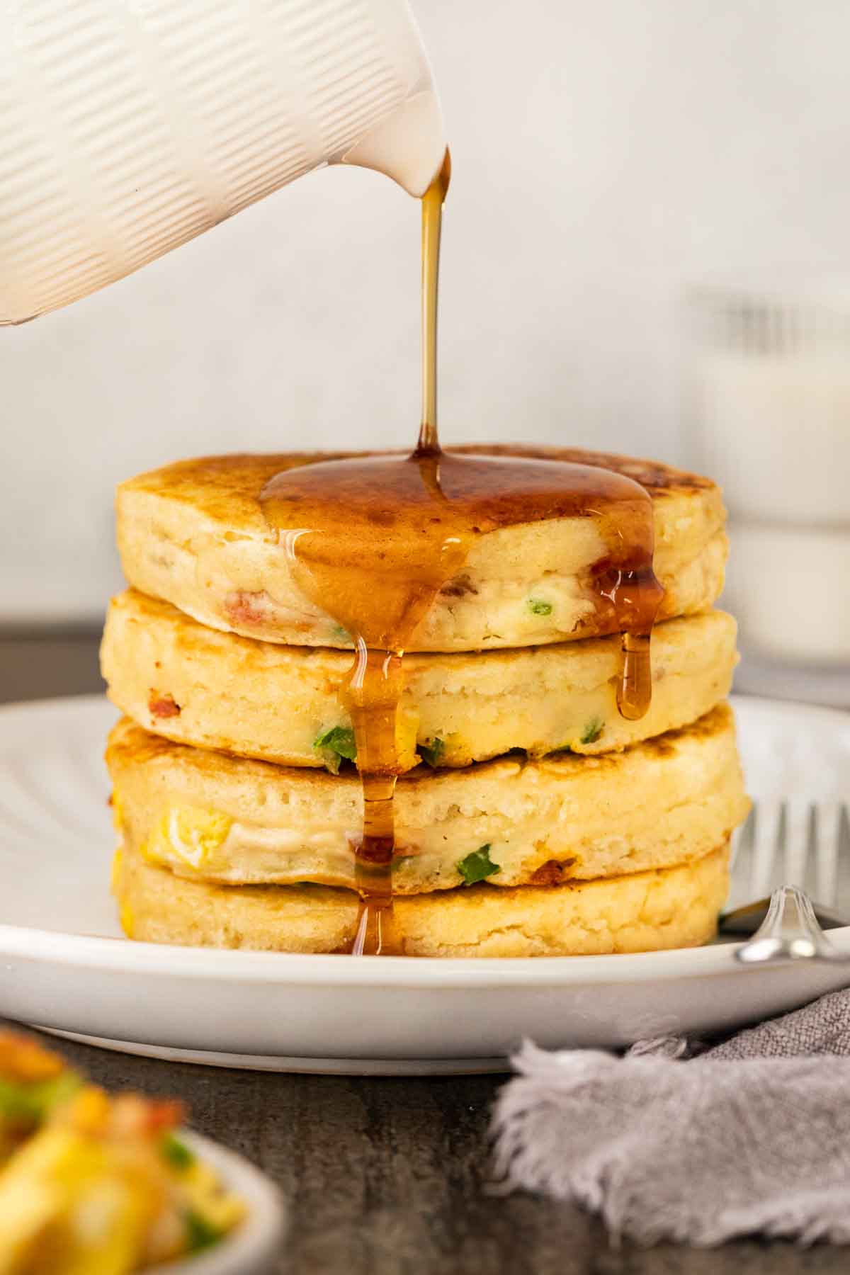 Loaded Breakfast Pancakes stack on serving plate with syrup
