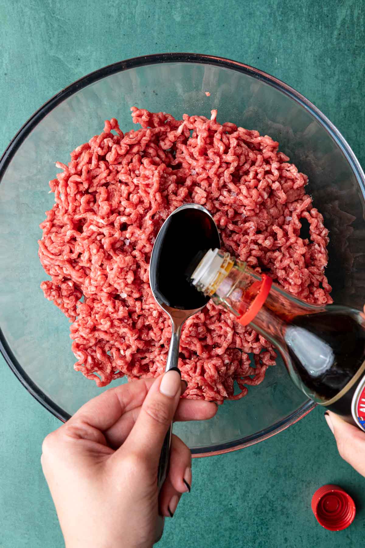 Loco Moco adding soy sauce to spoon over bowl of ground beef