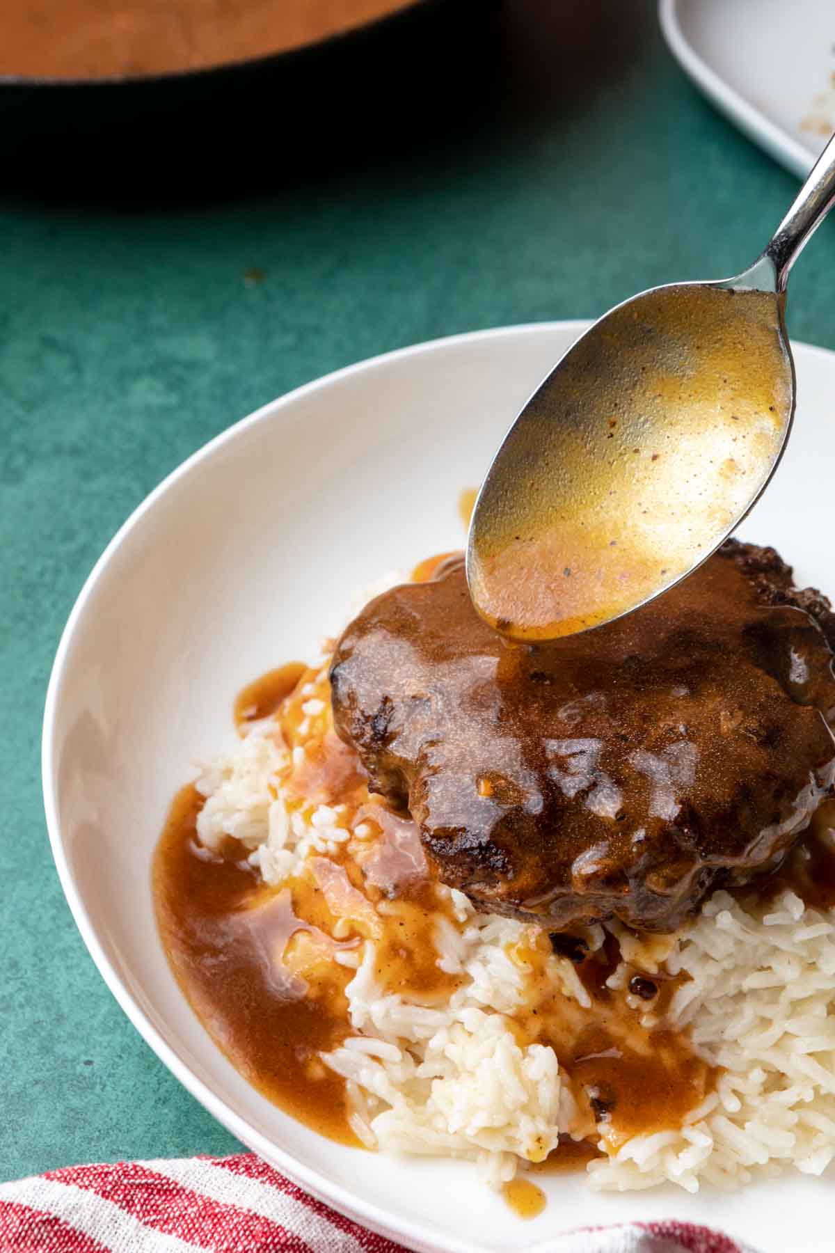 Loco Moco spooning gravy over patty and rice on plate