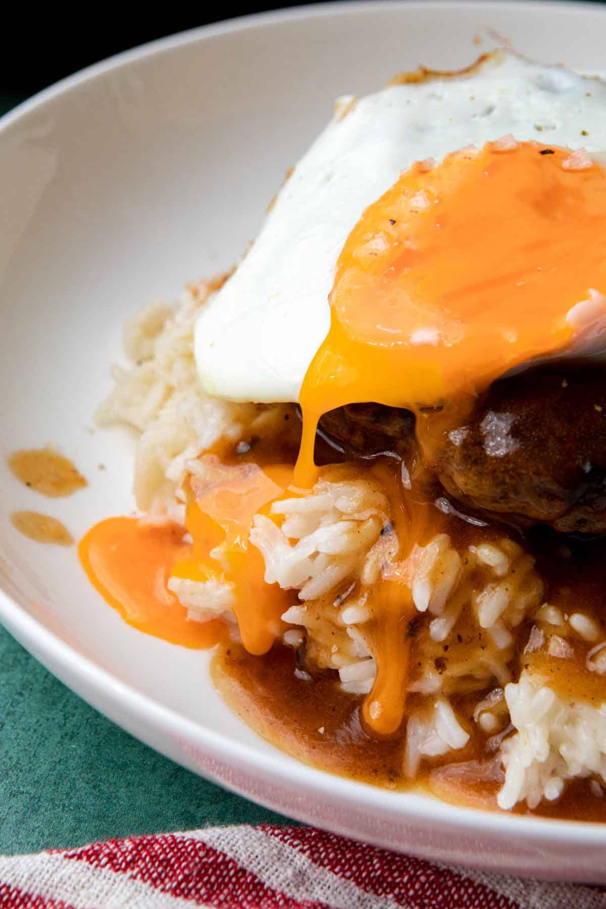 Loco Moco assembled dish on plate, egg yolk dripping down