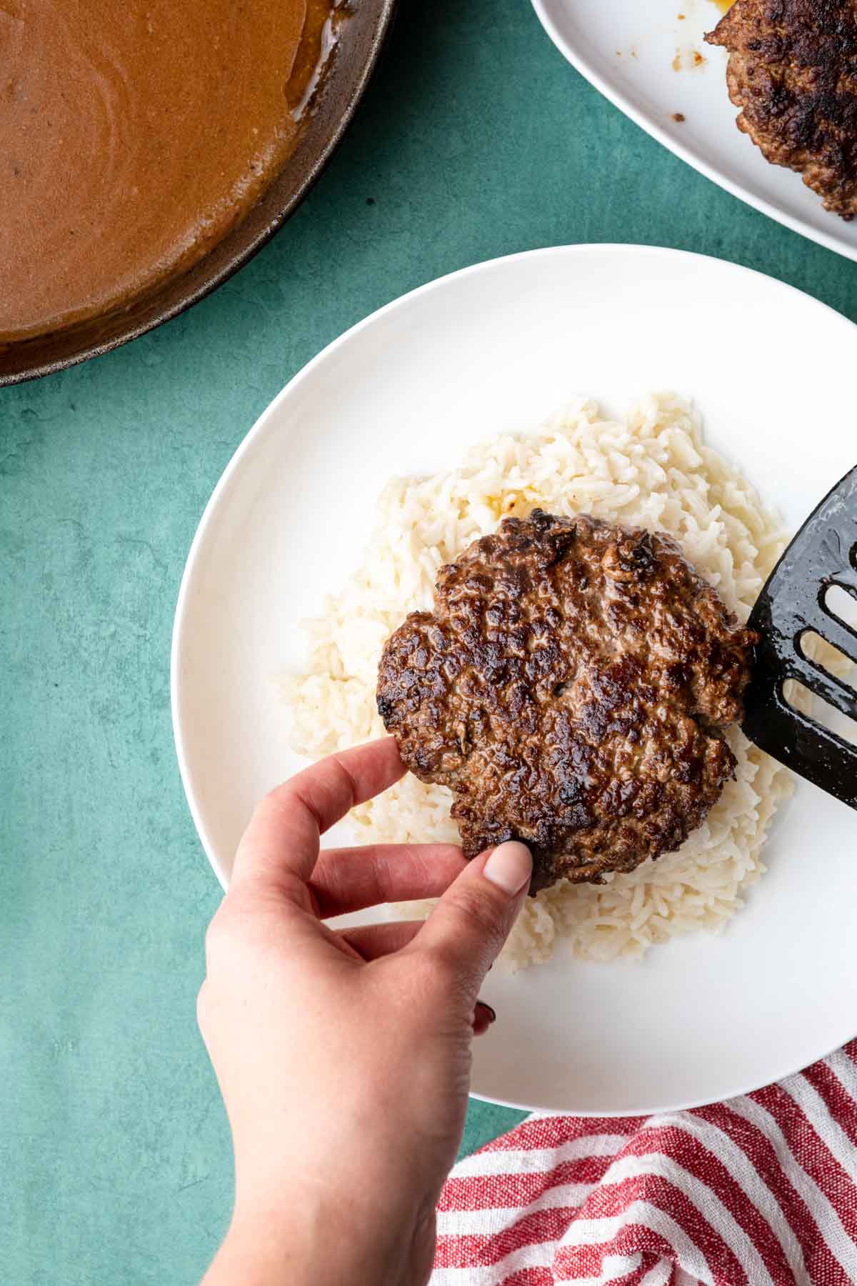 Loco Moco adding cooked patty to rice on plate