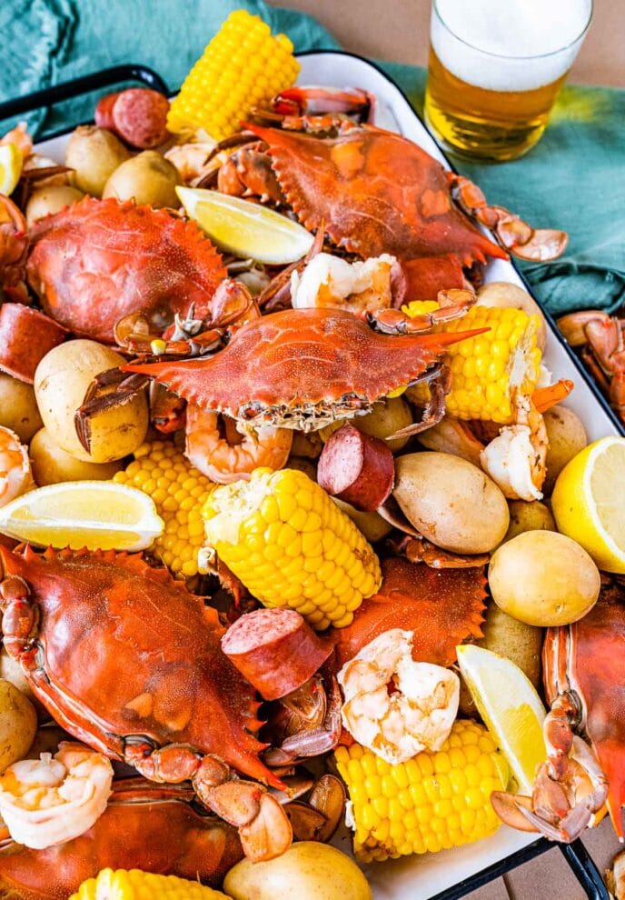 Low Country Boil cooked crab, corn, sausage, and potatoes on platter with melted butter