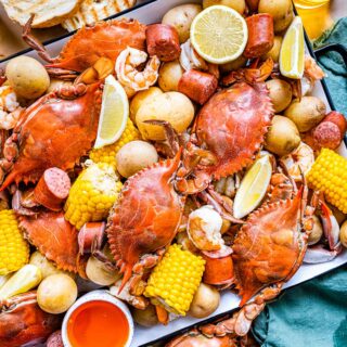 Low Country Boil cooked crab, corn, sausage, and potatoes on platter with toasted bread and melted butter