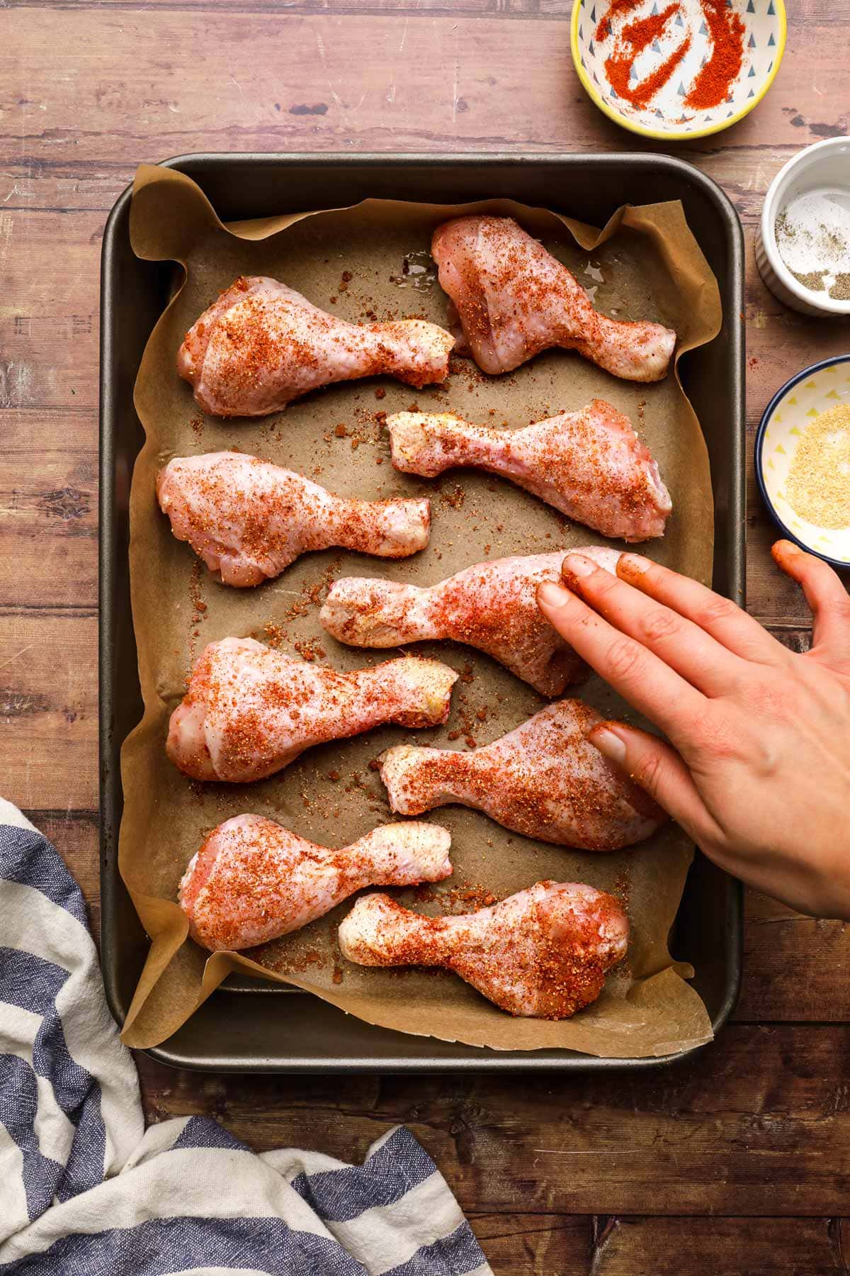 Oven Baked Chicken Drumsticks on baking pan applying seasoning