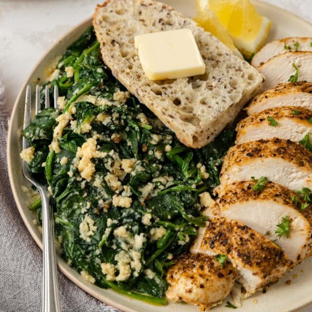 Parmesan Spinach Casserole on serving plate with chicken and bread 1x1