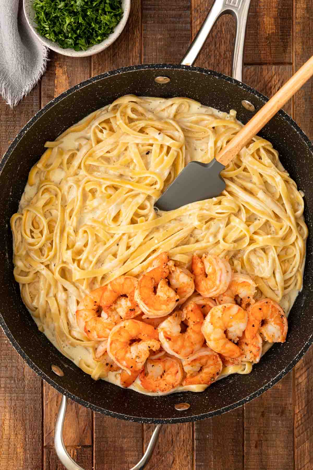 Classic Shrimp Alfredo adding cooked shrimp to pasta and sauce in cooking pan