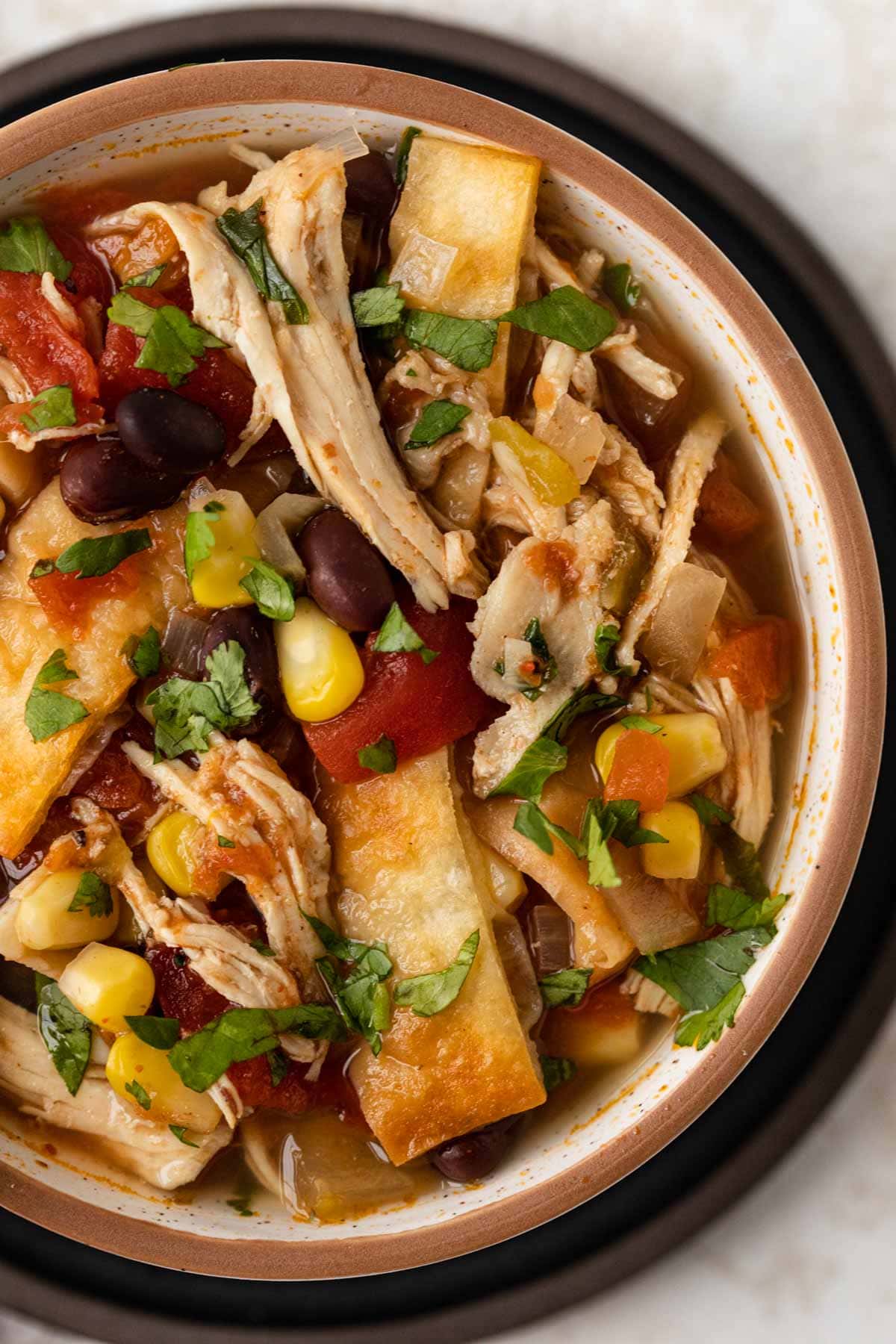 Slow Cooker Chicken Tortilla Soup in bowl with wooden spoon top view