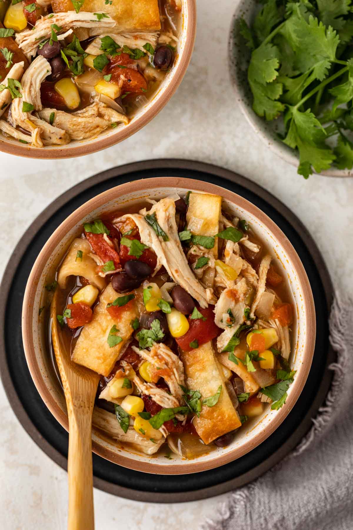 Slow Cooker Chicken Tortilla Soup in bowl with wooden spoon top view