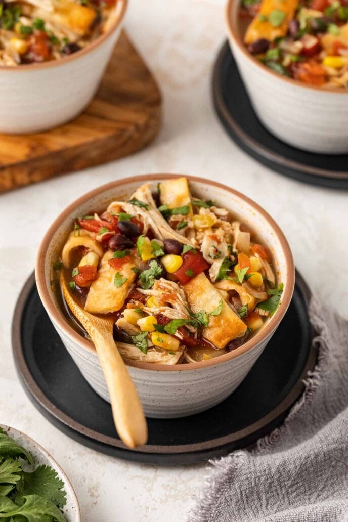 Slow Cooker Chicken Tortilla Soup in bowl with wooden spoon side angle view