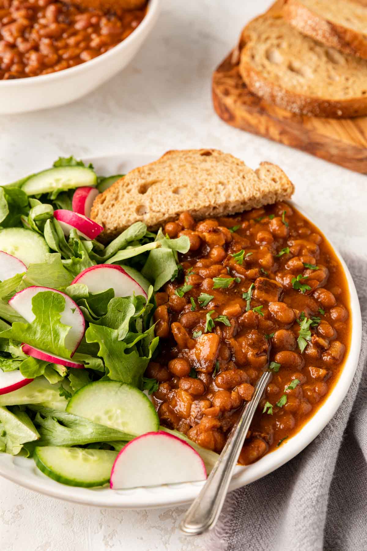 Slow Cooker Pork and Beans on plate with salad and bread