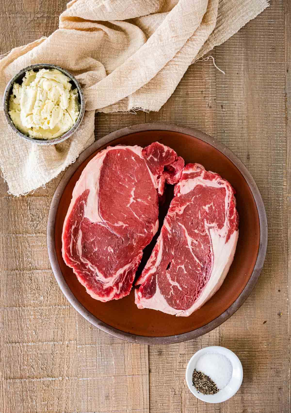Air Fryer Ribeye Steaks raw steaks on plate and butter in dish