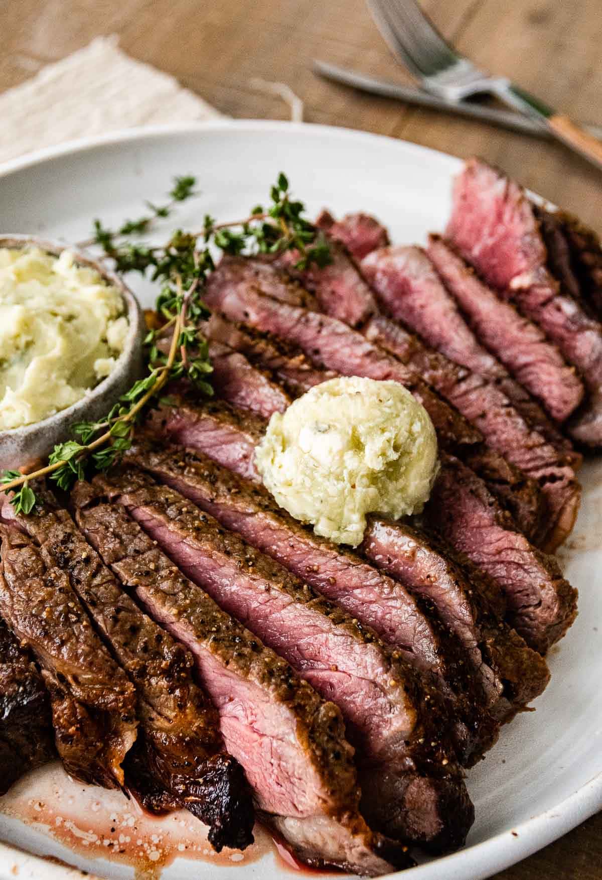 Air Fryer Ribeye Steaks one steak sliced on plate with blue cheese butter on top