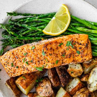 Broiled fish filet on dinner plate with asparagus and potatoes.