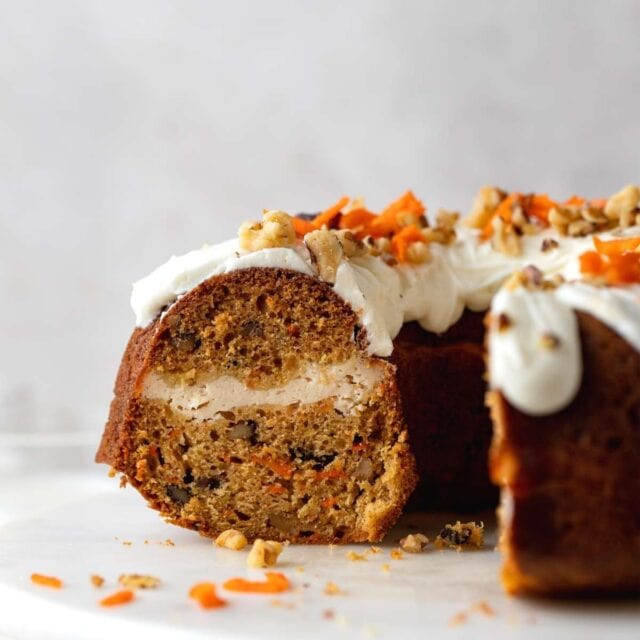 Carrot Cheesecake Bundt Cake with slices removed on cake stand 1x1