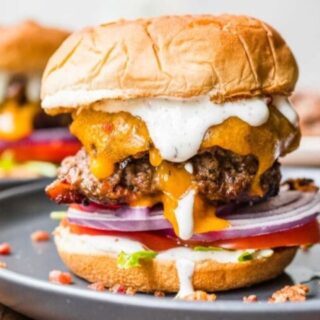 A burger stacked with onion, cheese and a bun.