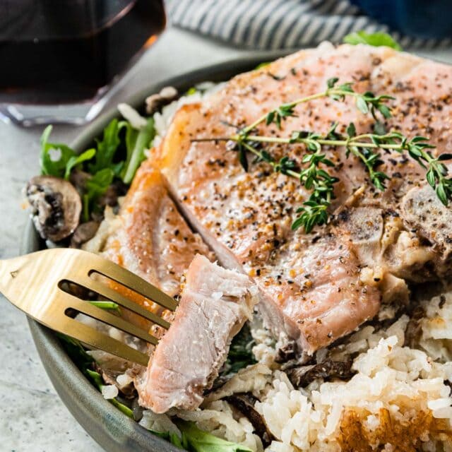 Creamy Mushroom Baked Pork Chops and Rice on serving plate cut with piece on fork 1x1