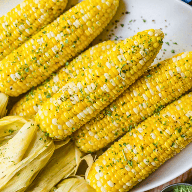 grilled yellow kernels on a cob stacked on one another on a white plate