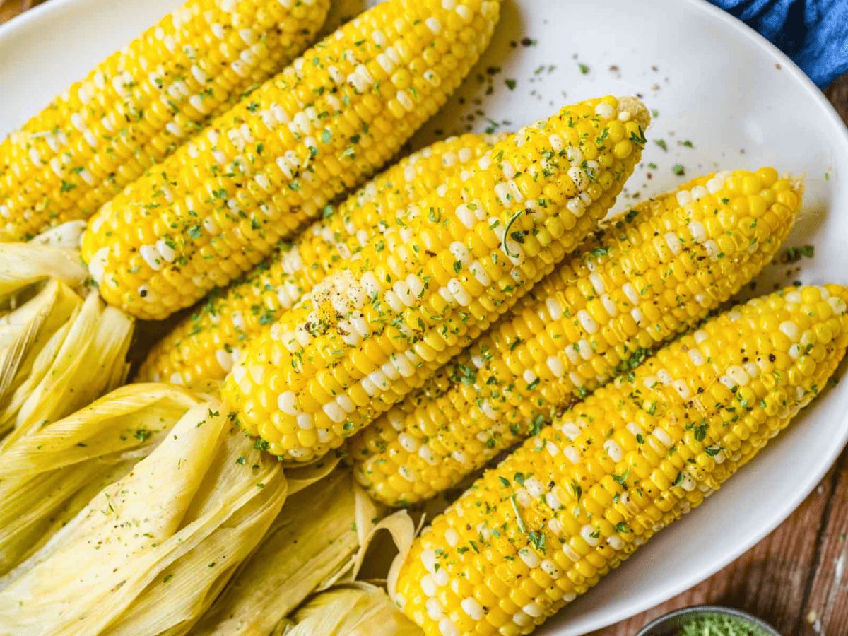 grilled yellow kernels on a cob stacked on one another on a white plate