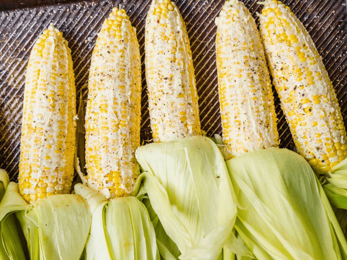 corn covered in butter and spices on a baking sheet