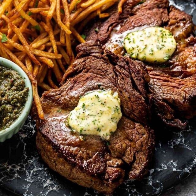 compound butter on steak on a plate with fries
