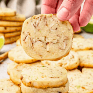 stack of cookies with hand holding one and cookies in the background