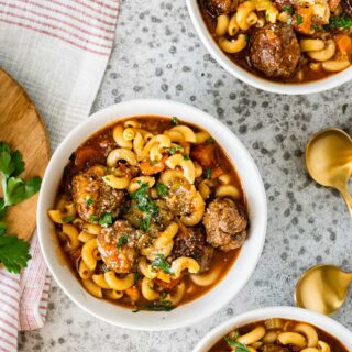 Bowl of soup with pasta, meatballs, and vegetables.