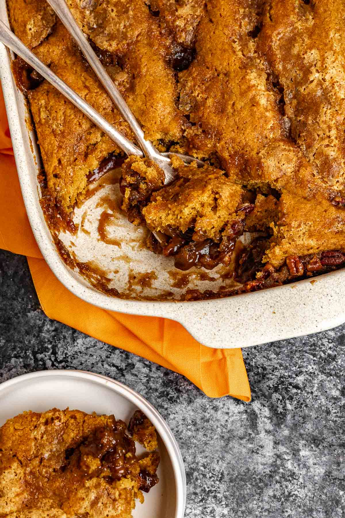 Pumpkin Cobbler baked in dish with slice removed and spoons