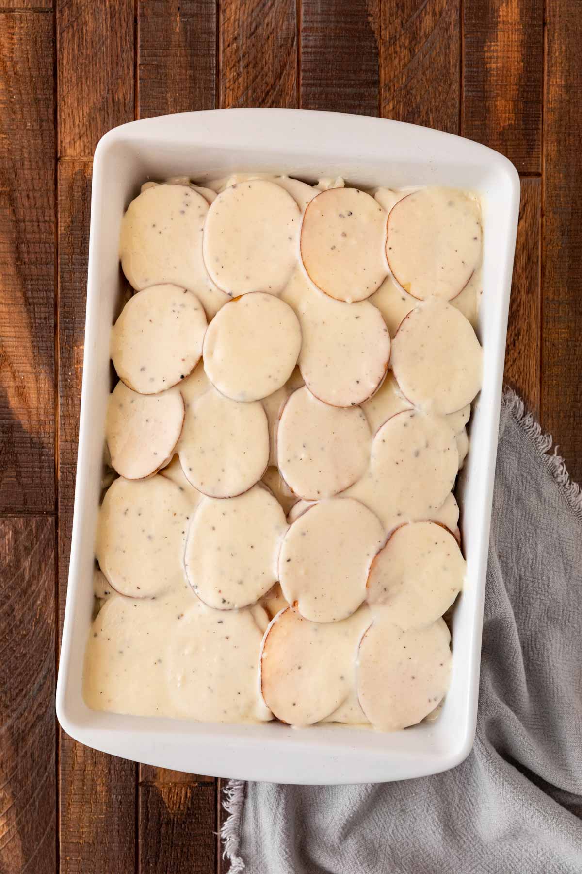 Scalloped Potatoes and Ham béchamel sauce added to baking pan