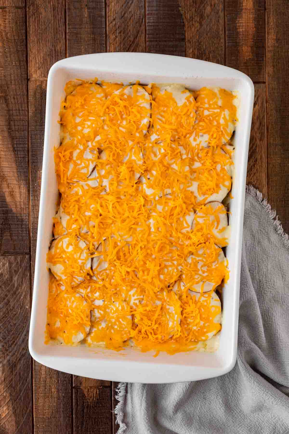 Scalloped Potatoes and Ham sprinkled with cheese in baking pan before baking