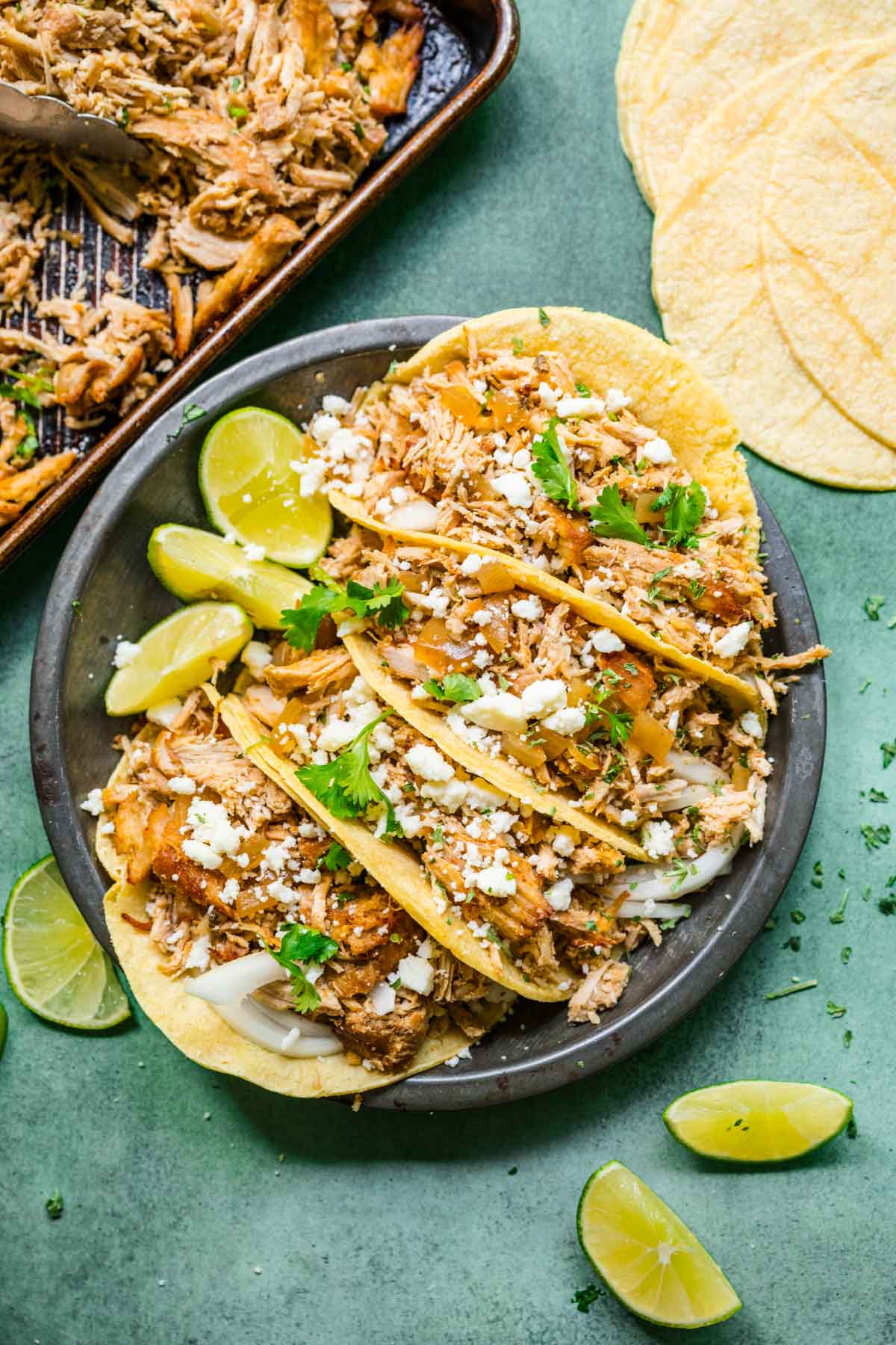Slow Cooker Pork Carnitas four tacos on plate with cheese and cilantro