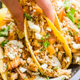 four tacos with cheese and cilantro hand holding middle taco