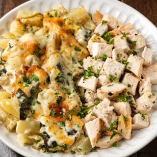 Creamy potato and spinach dish on dinner plate with chicken.
