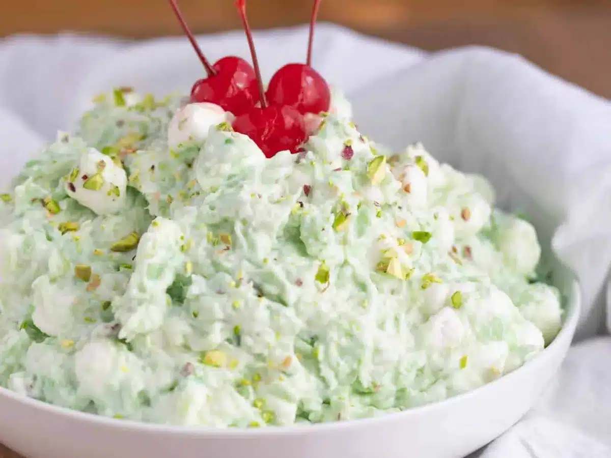 green salad in white bowl topped with cherries