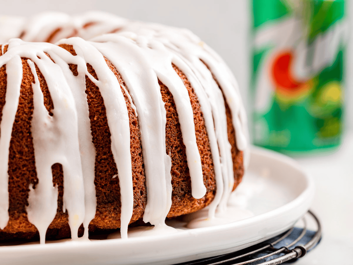 bundt cake with icing on a white plate with soda in the background