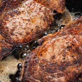 Aerial view of two cooked steaks in cast iron skillet