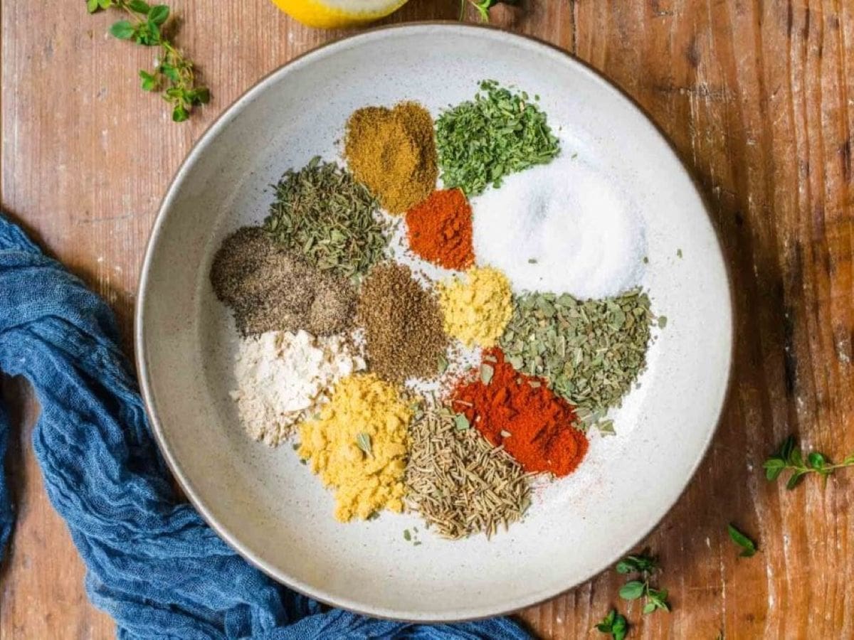Chicken Seasoning Blend is a savory spice blend for chicken made from rosemary, paprika, cumin, basil, rosemary, garlic powder, and more! Spices in a white bowl.