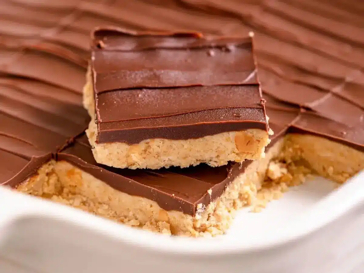 Bars in a baking pan with a bottom layer of peanut and top layer of chocolate