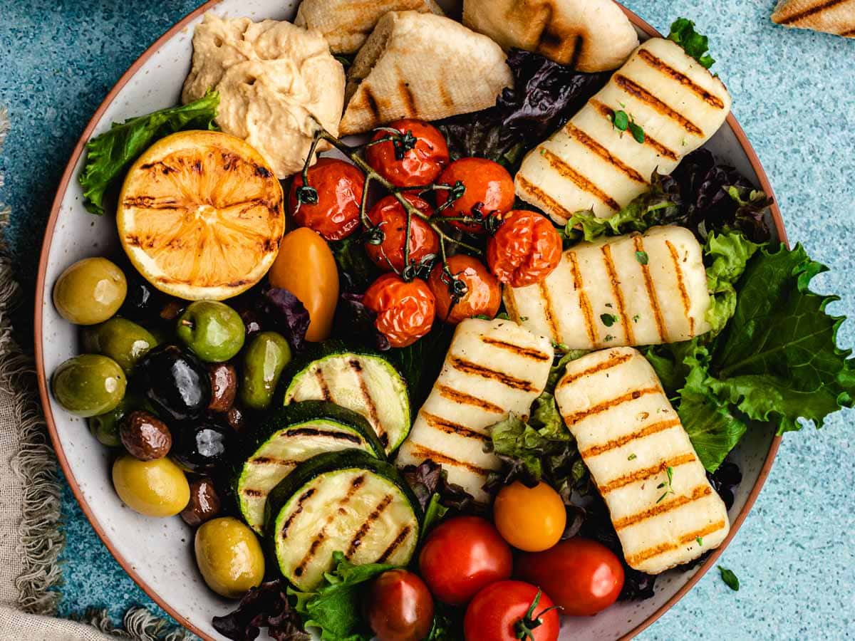 Appetizer plate filled with grilled vegetables, and cheese slices.
