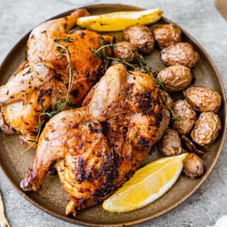 Cornish hens on dinner plate with potatoes.