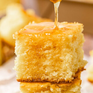 Dripping honey on stack of two squares of cornbread.