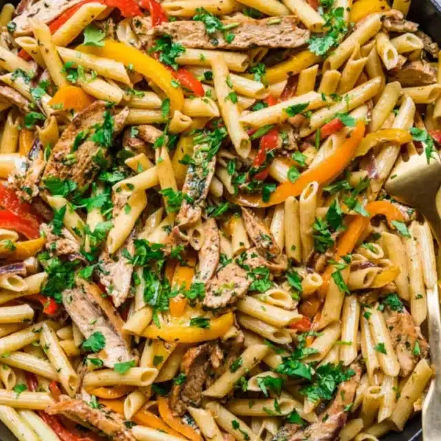 Close up of penne pasta with chicken and peppers.