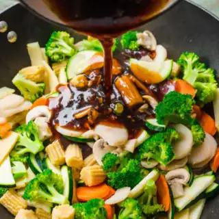 Savory sauce being poured on top of vegetables.