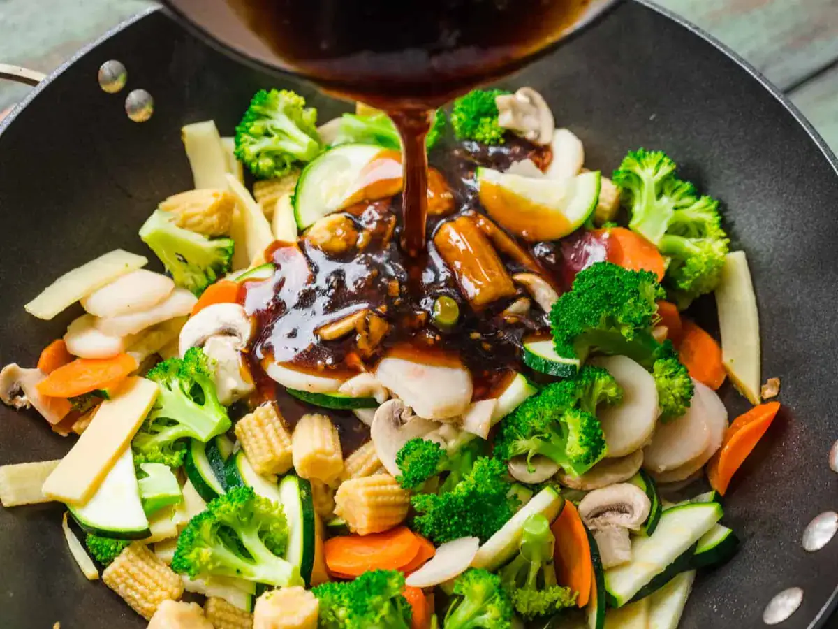 Savory sauce being poured on top of vegetables.