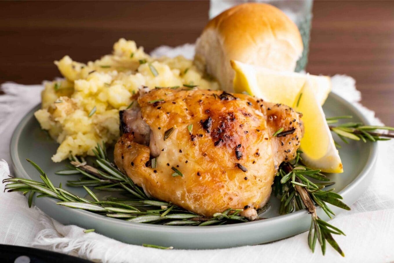 Baked Rosemary Chicken on plate with mashed potatoes and dinner roll